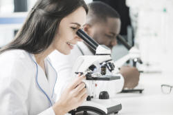 Cheerful medic woman looking at microscope Free Photo